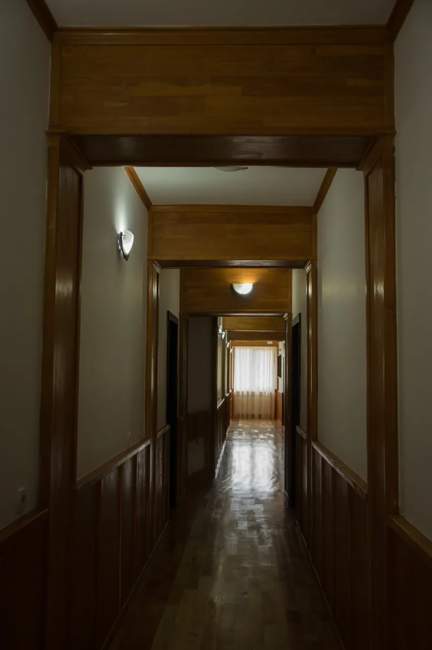 Coridorul de la etaj, cu tavan de lemn și uși de cameră pe o parte.