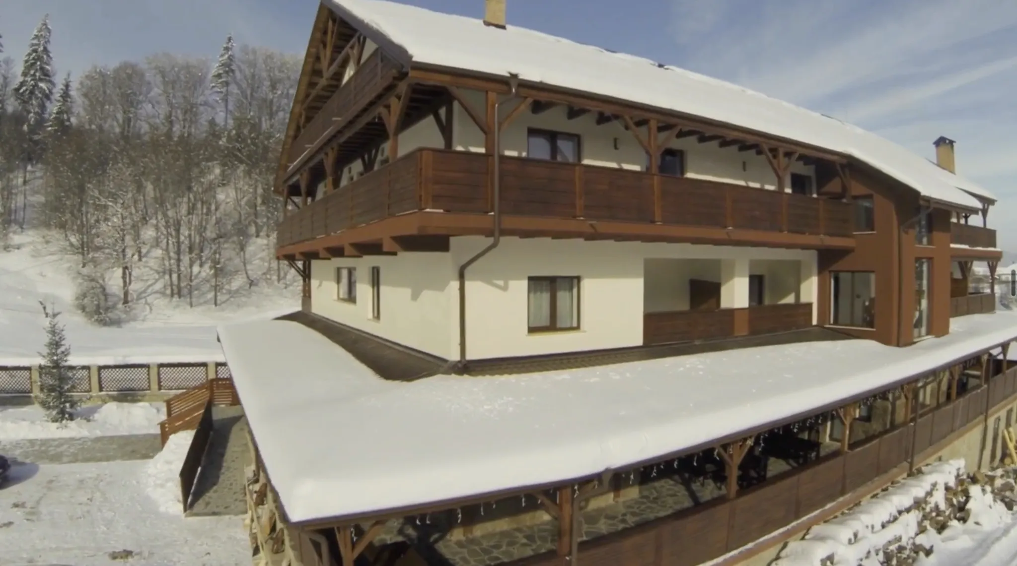 Vedere aeriană de aproape, iarna: balconul de la etajul de sus, cel de la mijloc și acoperișul terasei încărcat de zăpadă, cu țurțuri pe marginea lui.
